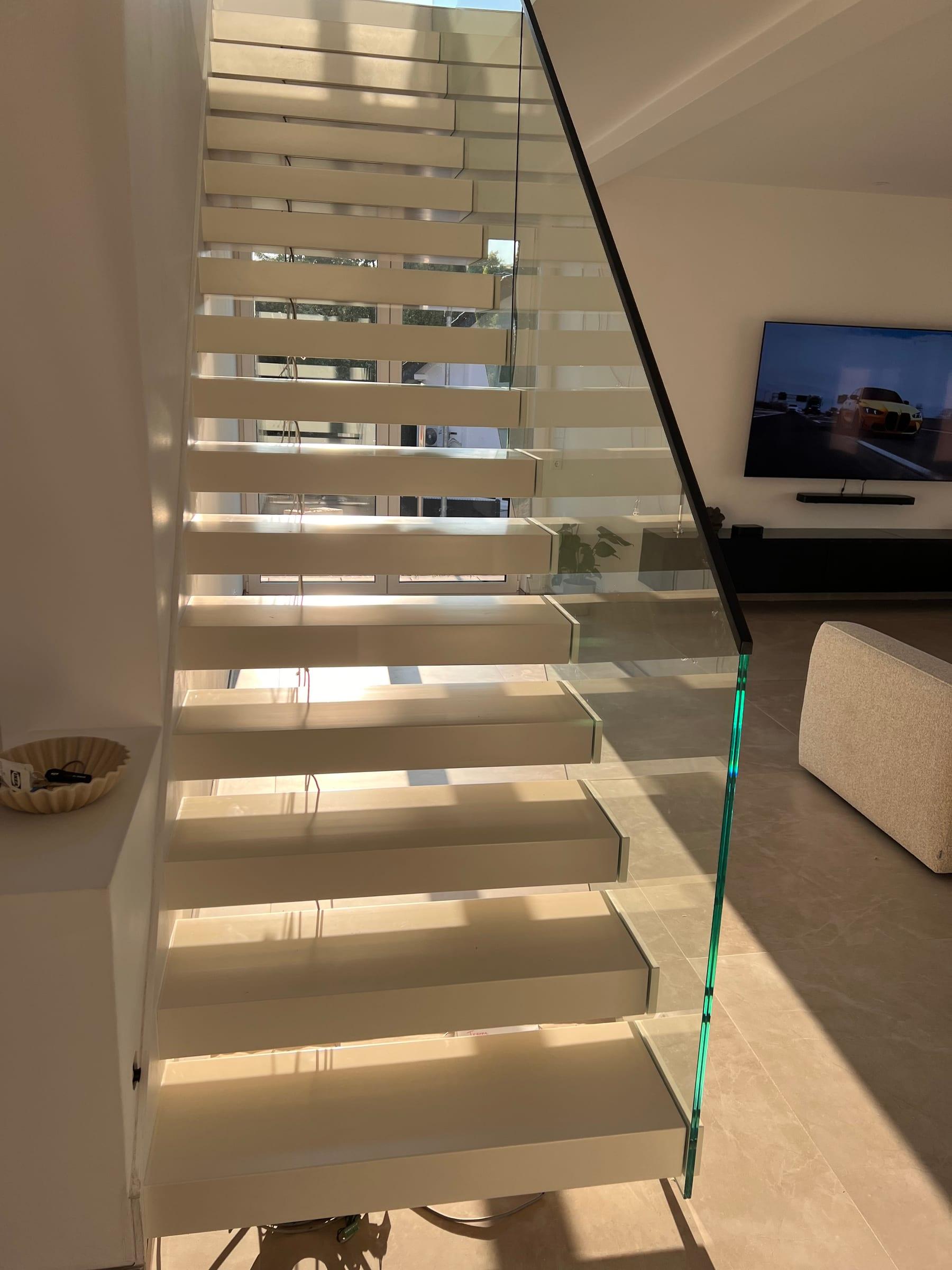 Freitragende weiße Treppe mit rahmenloser Glasbrüstung im Wohnraum